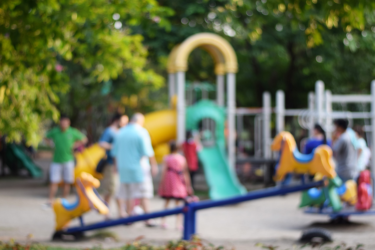 colorful playground with children and parents in park blur background